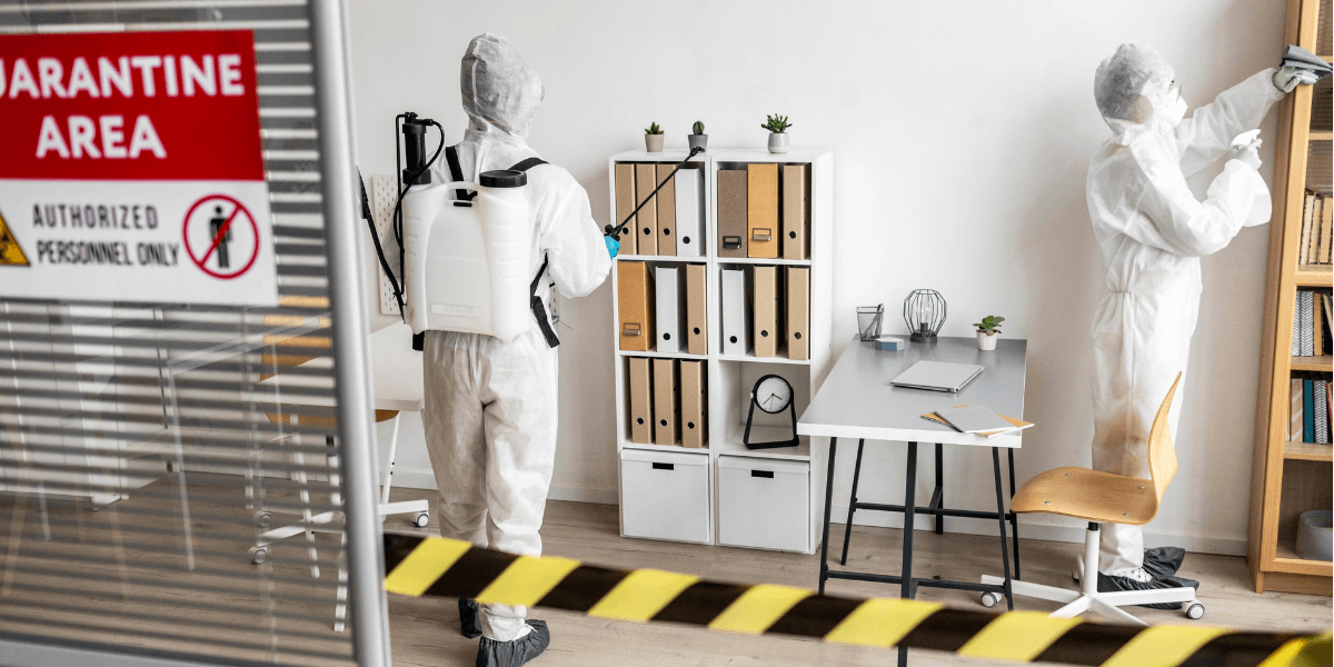 Two individuals in white suits stand before a designated quarantine area, emphasizing safety and health protocols.