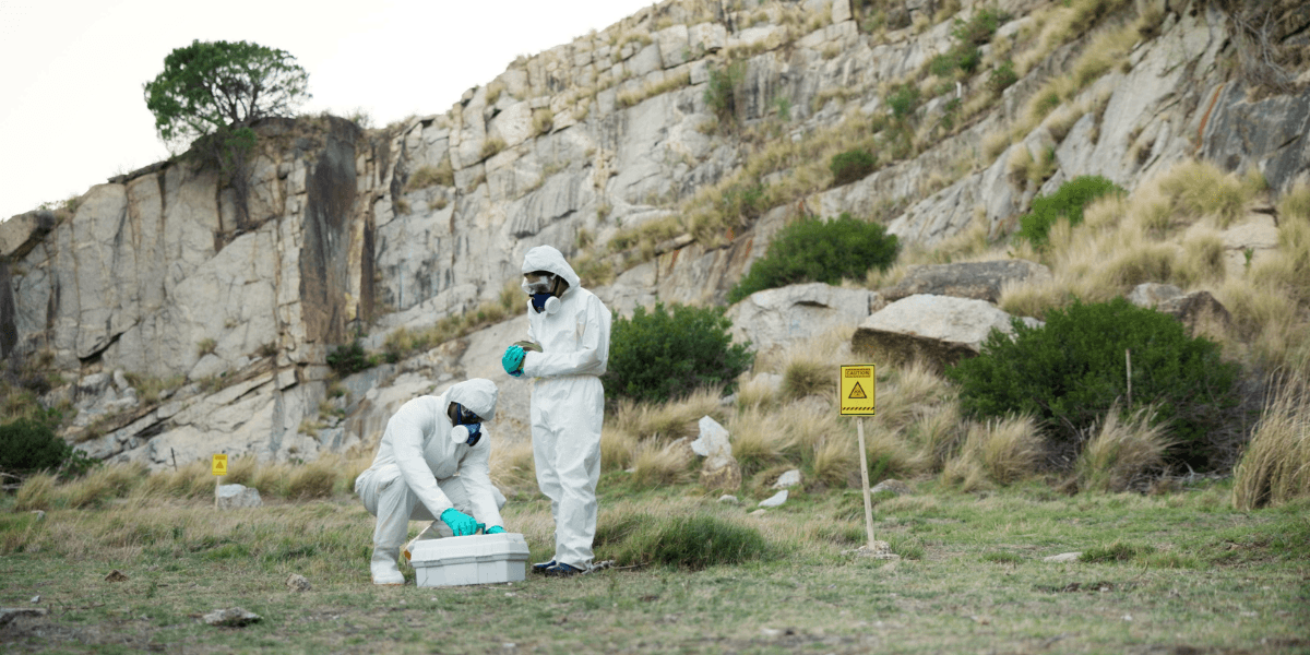 Climate Change and Pest Activity in Nevada: Why Pests Are Active Longer Than Ever 1 Two individuals in protective suits stand beside a large rock, emphasizing safety in a potentially hazardous environment.